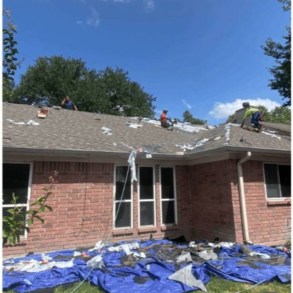 Roofing crew removing old shingles during residential roof replacement in Spring Texas
