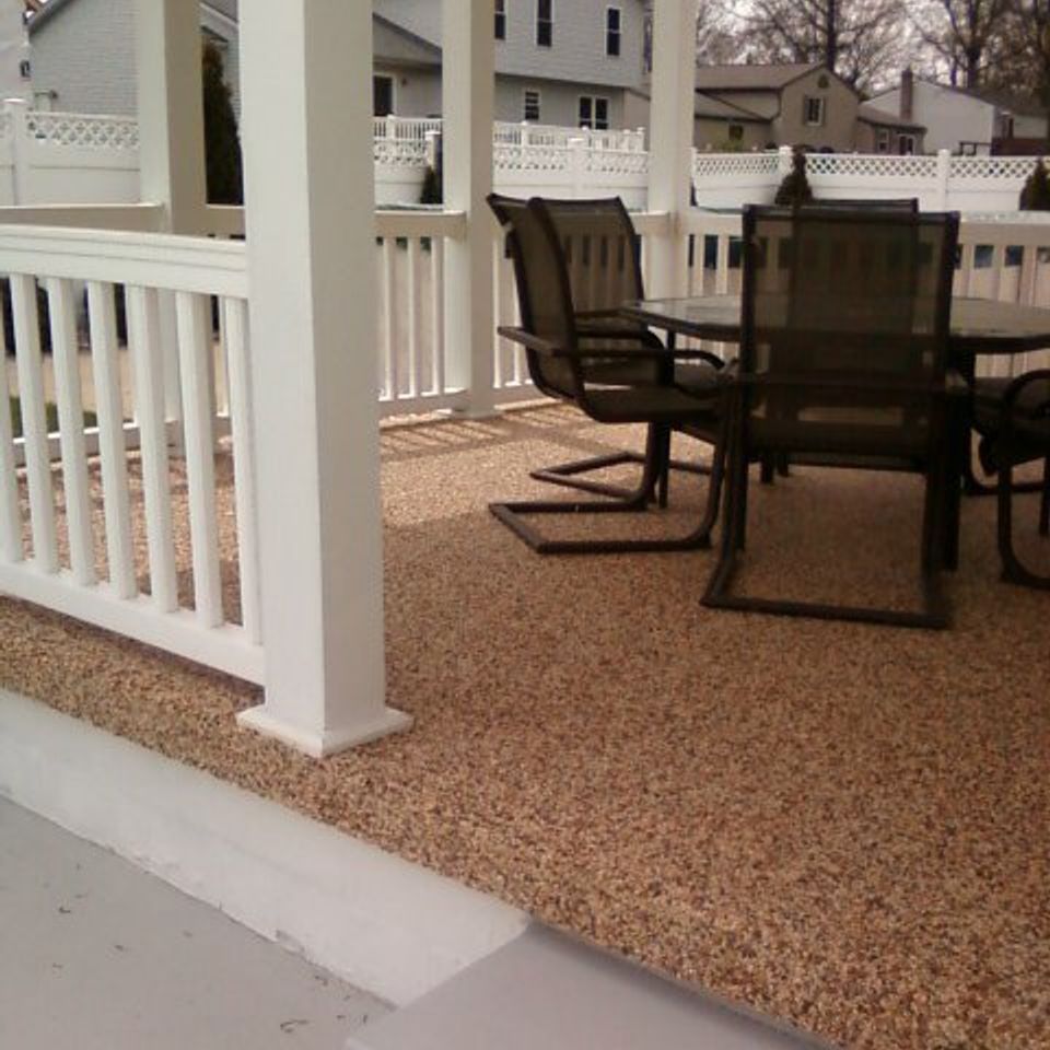 Covered porch with decorative stone flooring, white railings, and outdoor dining furniture.