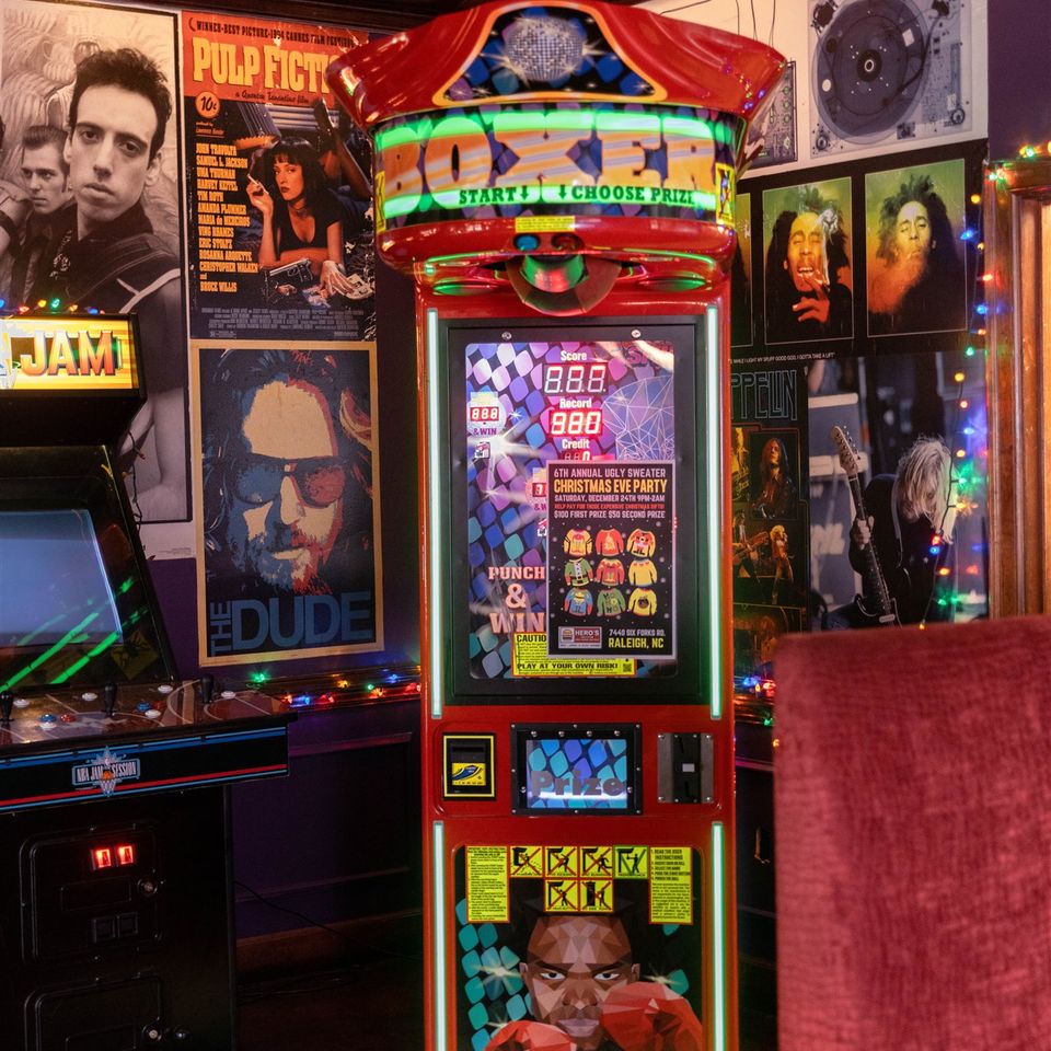 Boxing arcade machine with other games around it and large album art on the walls around it