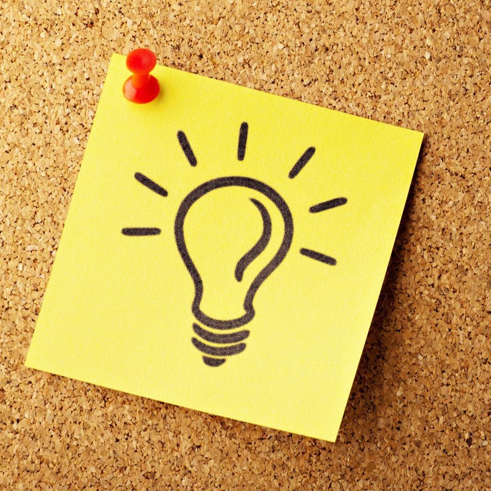 Yellow sticky note with a hand drawn light bulb pinned to a cork board representing Brainstorm mental clarity IV therapy