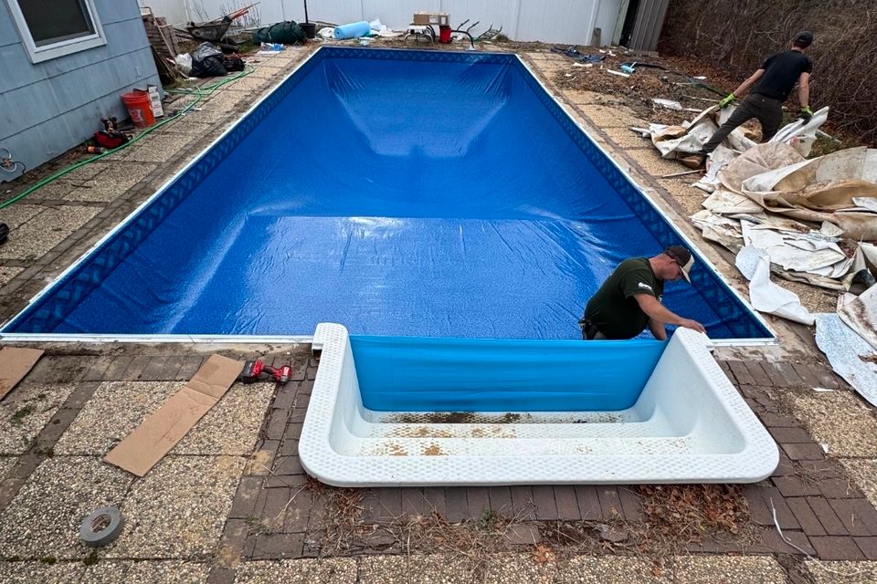 Crew fitting a new vinyl liner in a rectangular inground pool with the step unit removed