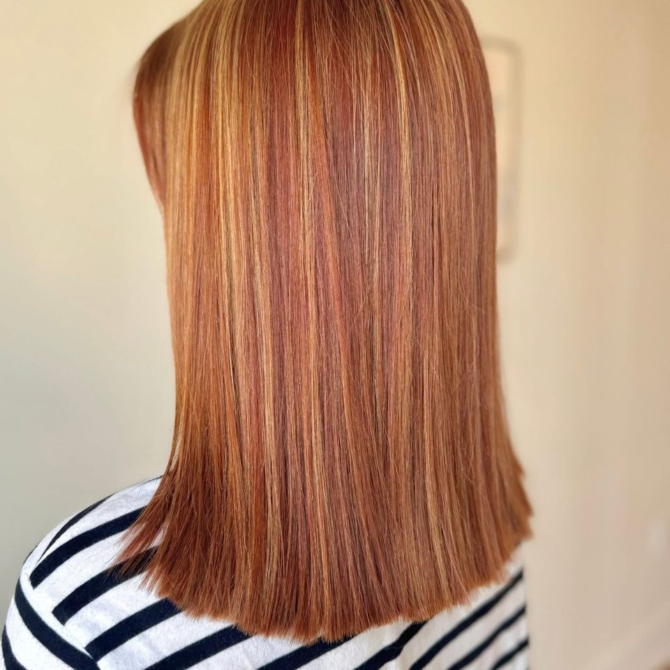 Medium straight copper red hair with blonde highlights and blunt ends after color service in Columbiana AL