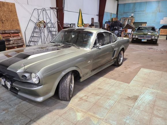 Classic Ford Mustang inside an auto glass shop for professional automotive glass repair and windshield replacement.