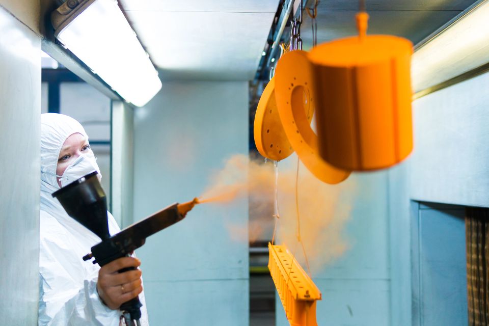A person powder coating an object the color orange