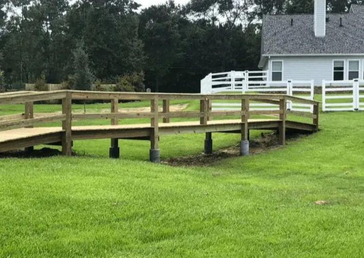 Finished wooden walkway bridge leading toward house