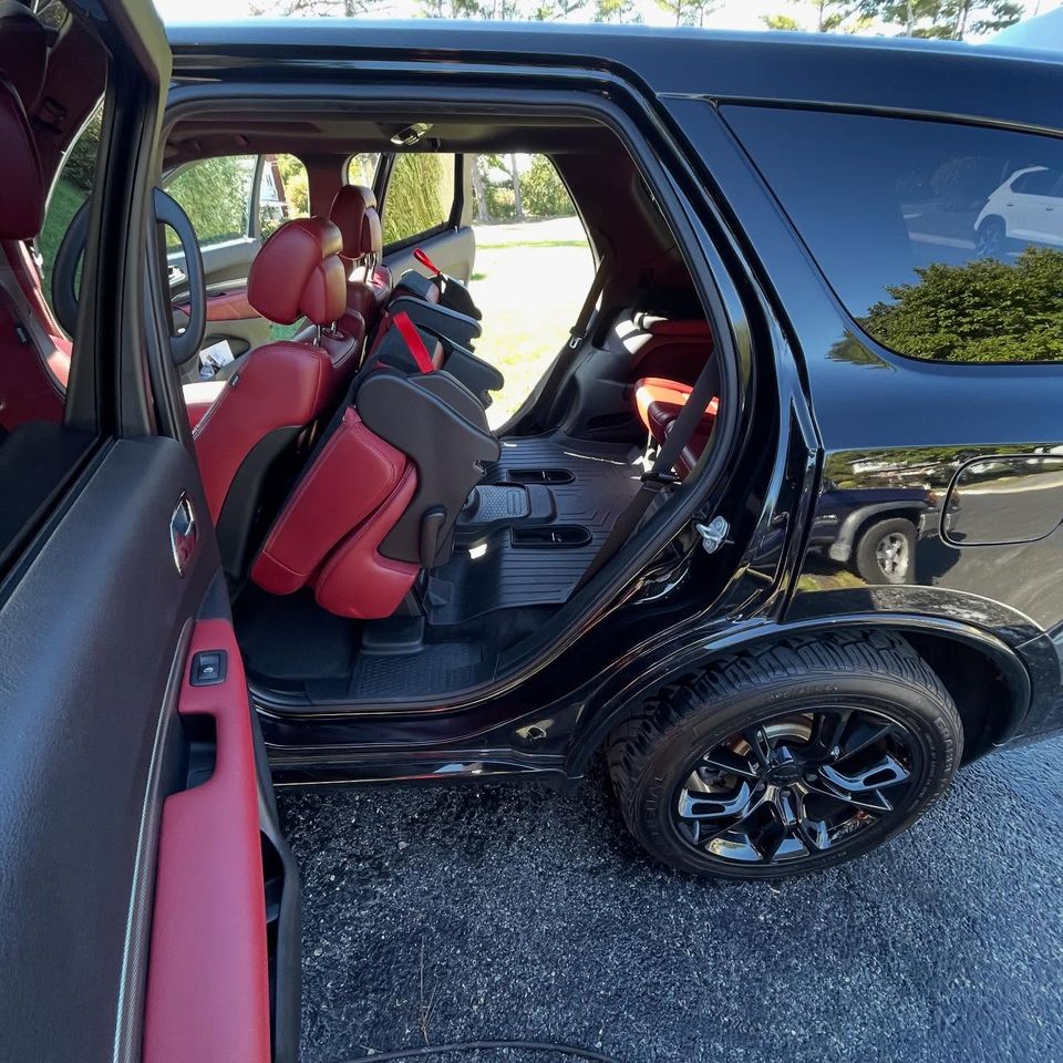Black Dodge Durango with clean red leather seats and all-weather mats after interior cleaning in Wilmington