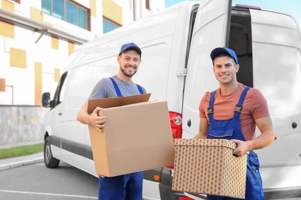 Two employees of I HAUL IT ALL in Ventura California loading boxes into a cargo van during a junk removal project.