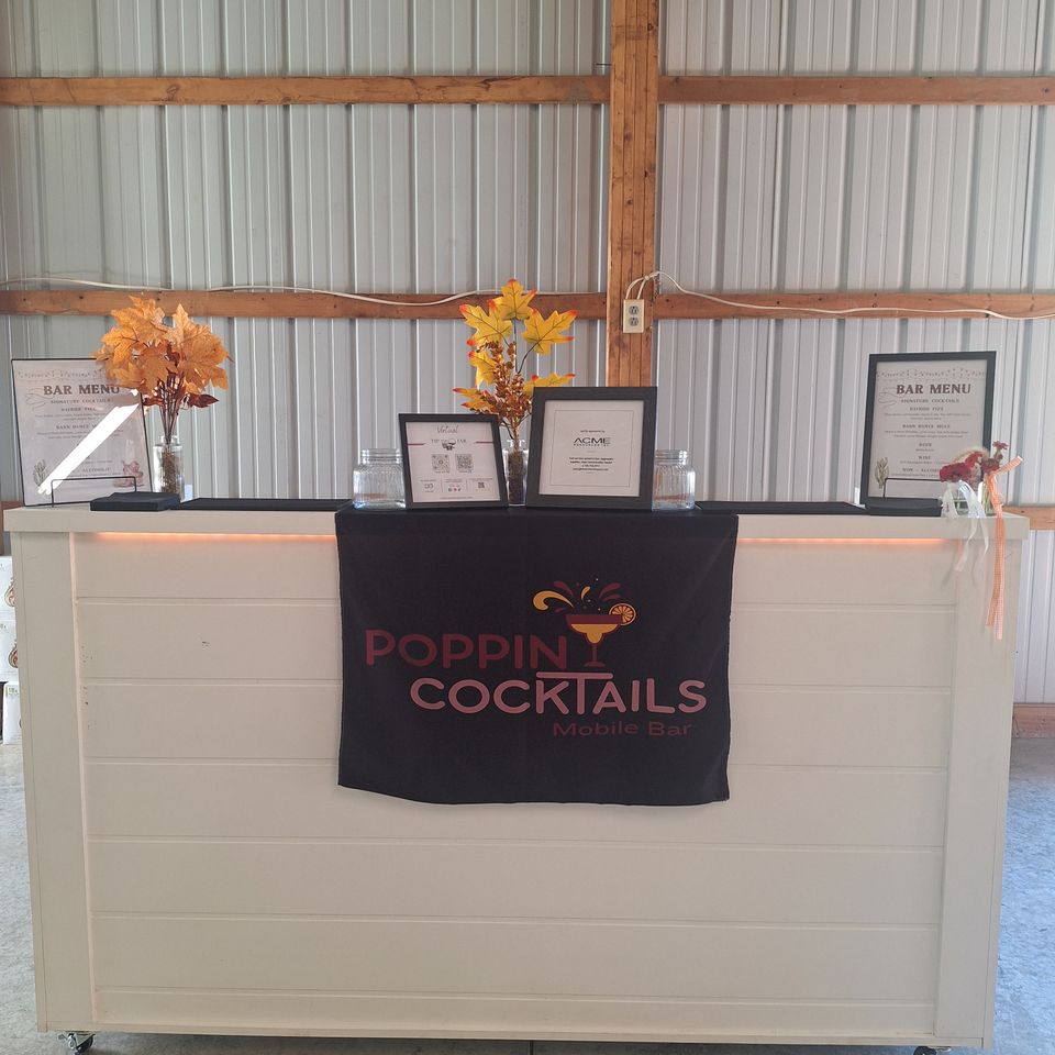 6-foot wooden mobile bar by Poppin Cocktails displayed with custom bar menus, floral accents, and event service accessories.