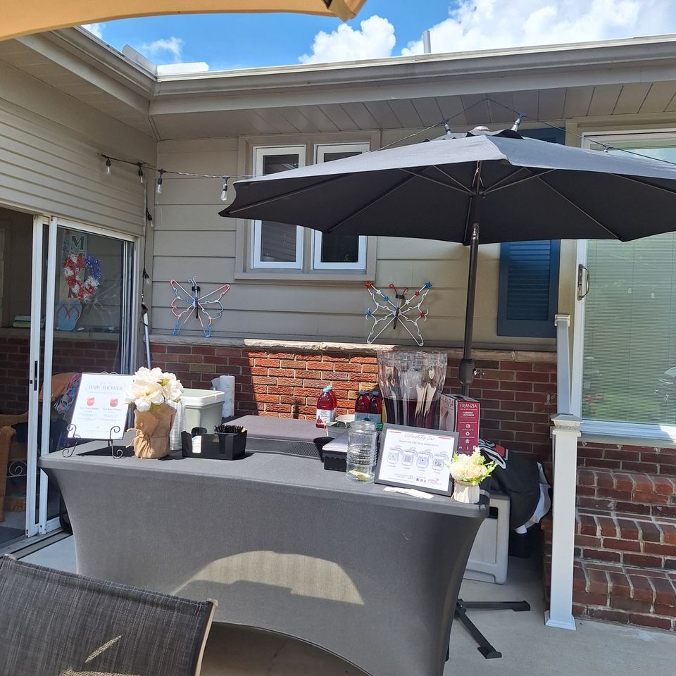 Custom table bar setup featuring drink menus, refreshments, floral décor, and beverage service for an event.