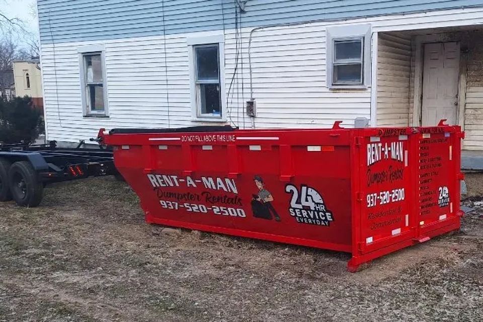 Rent-A-Man Dumpster Rentals dumpster placed beside a residential home.
