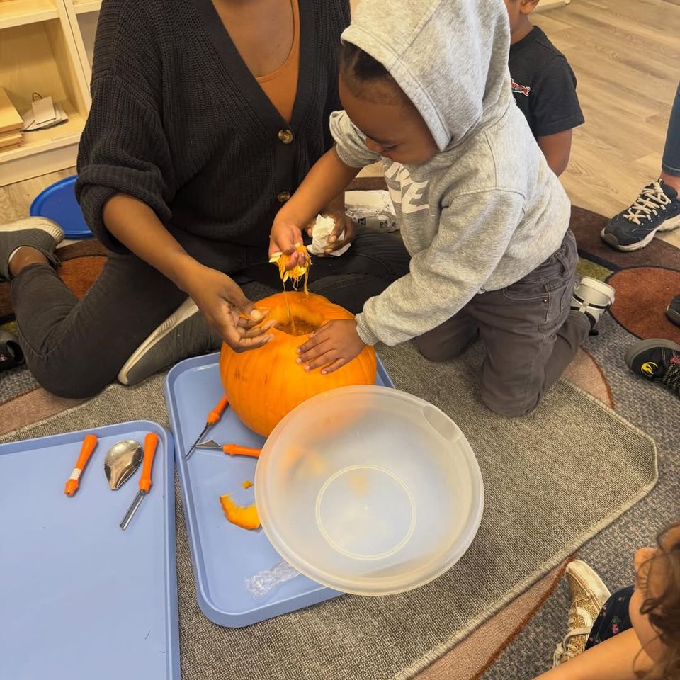 Teacher and toddler scooping seeds from a pumpkin during a fall daycare activity in Palmdale CA