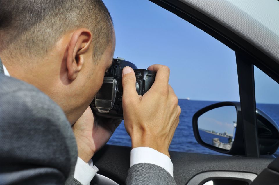A private investigator in his car taking photos