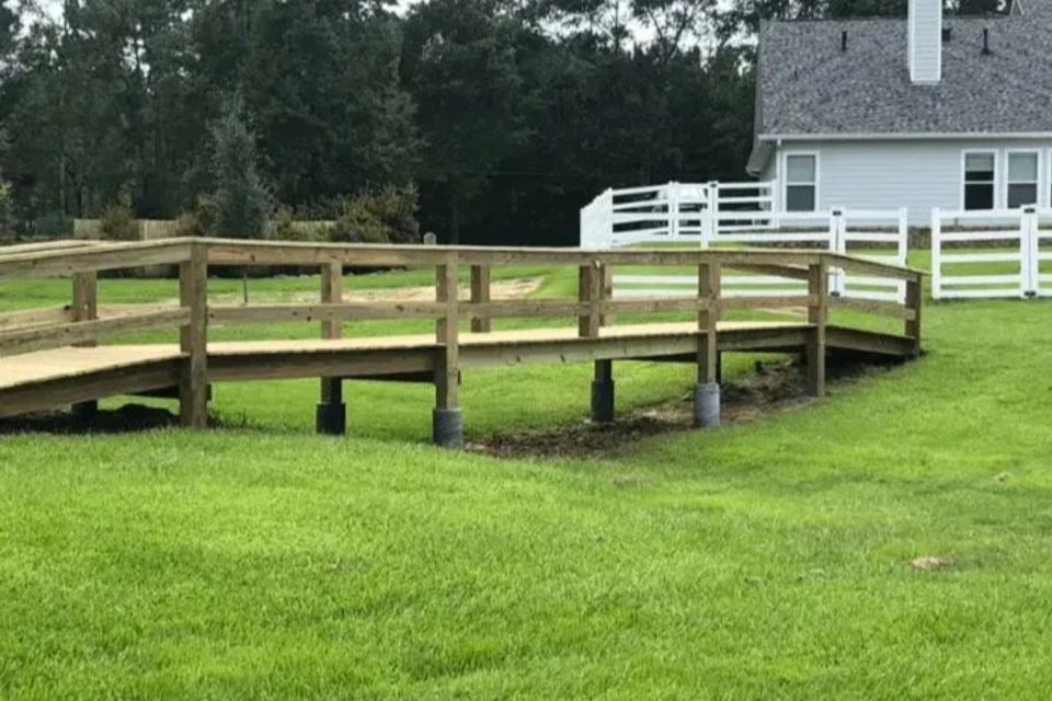 Finished wooden walkway bridge leading toward house