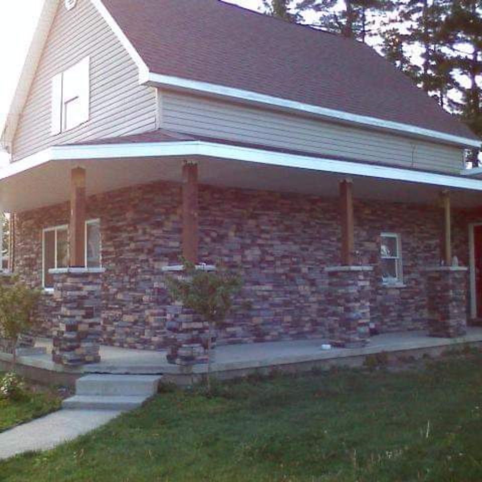 Home featuring veneer stone along the exterior walls and front porch columns.