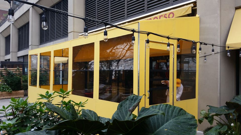 Yellow seasonal vestibule with clear vinyl panels enclosing a restaurant entrance Morso in New York City