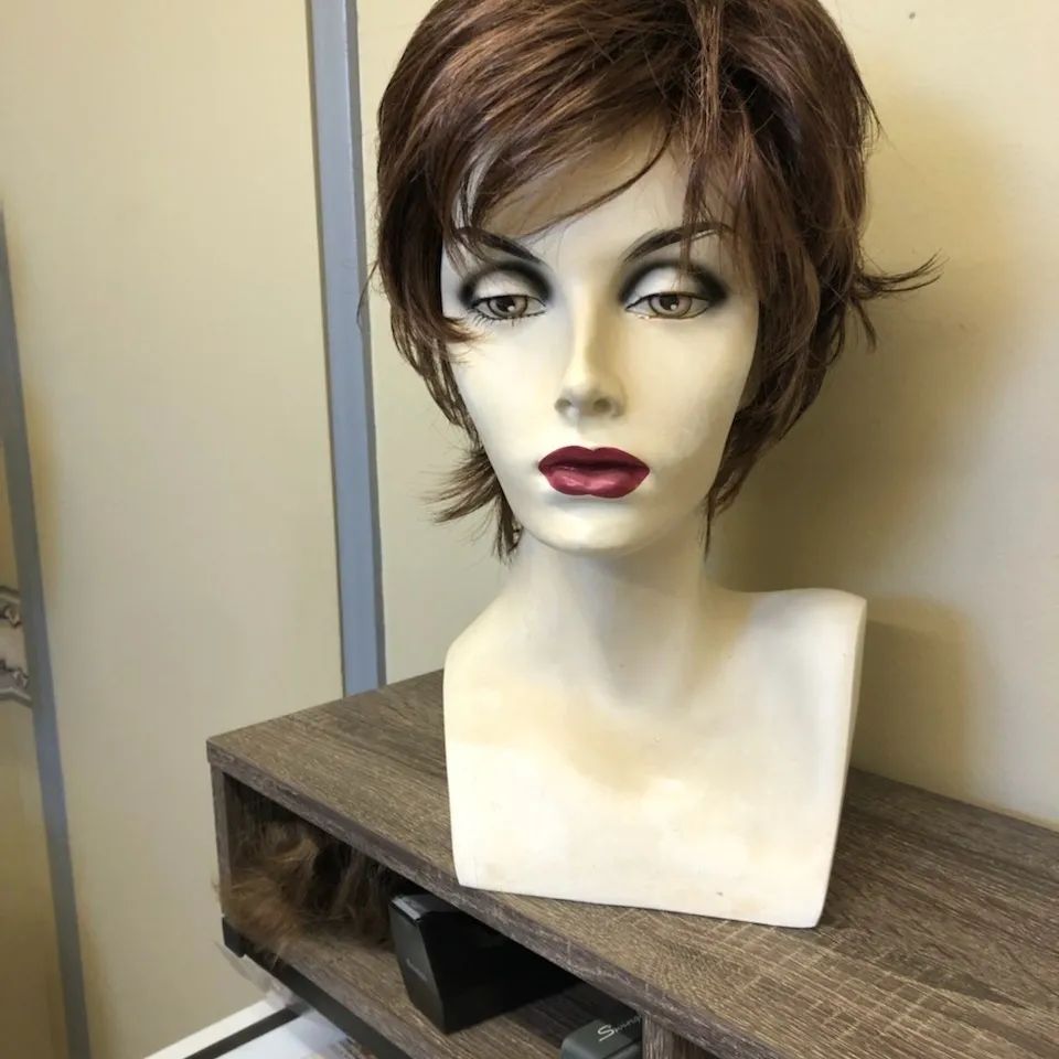 Short brown wig displayed on a mannequin head, showcasing a layered style with a natural appearance.