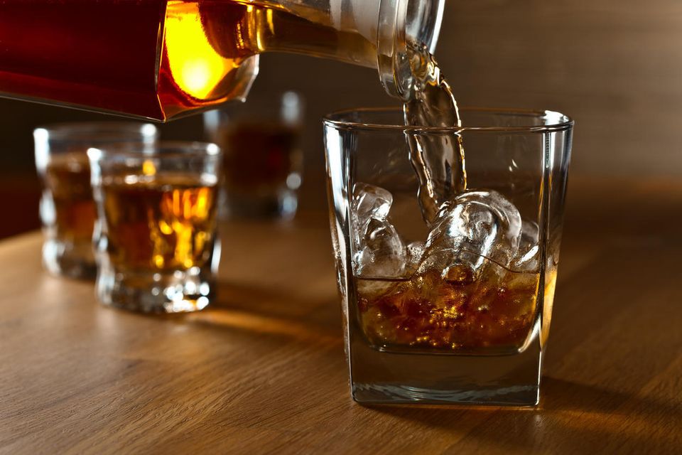 Pouring whiskey into glass with ice istock igorr1
