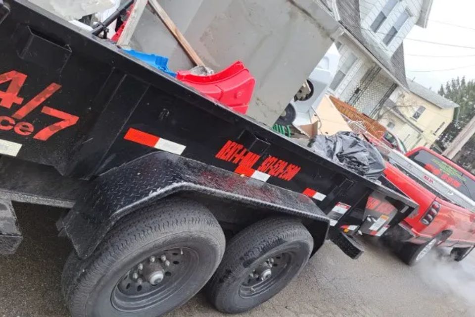 Rent-A-Man Dumpster Rentals trailer loaded with furniture and household debris for disposal.