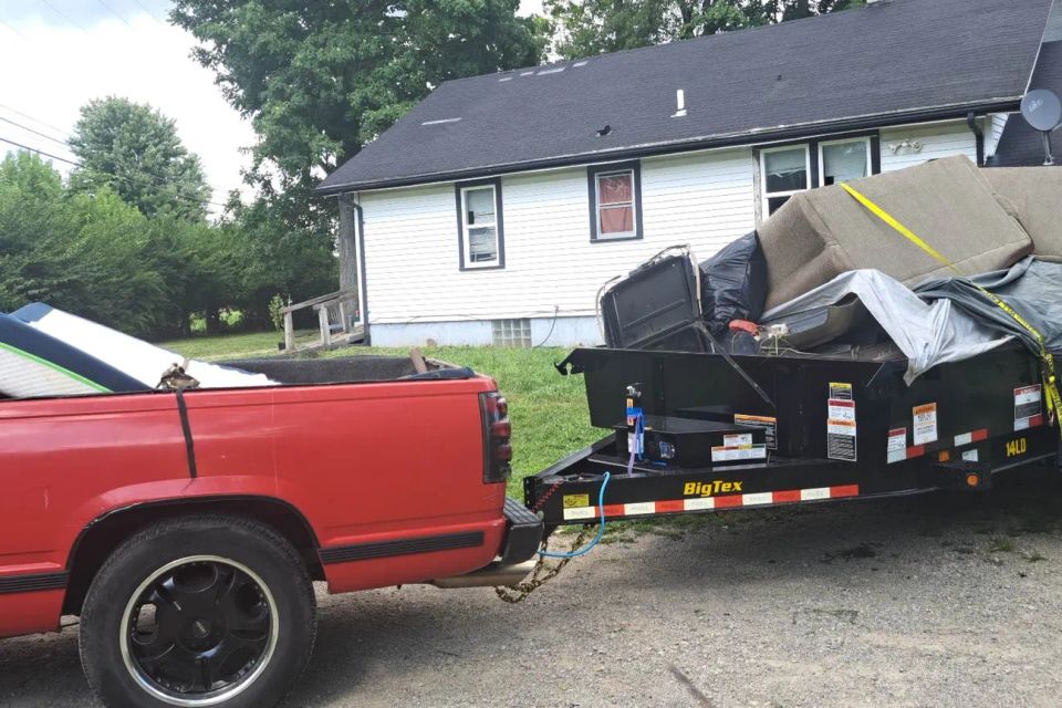Rent-A-Man Dumpster Rentals trailer loaded with mattresses, furniture, and household debris.