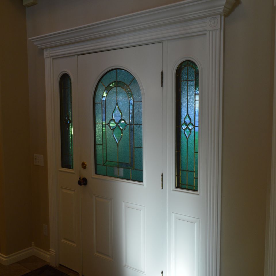 White entry door with leaded glass sidelights and decorative trim in a custom home in Trout Creek MT