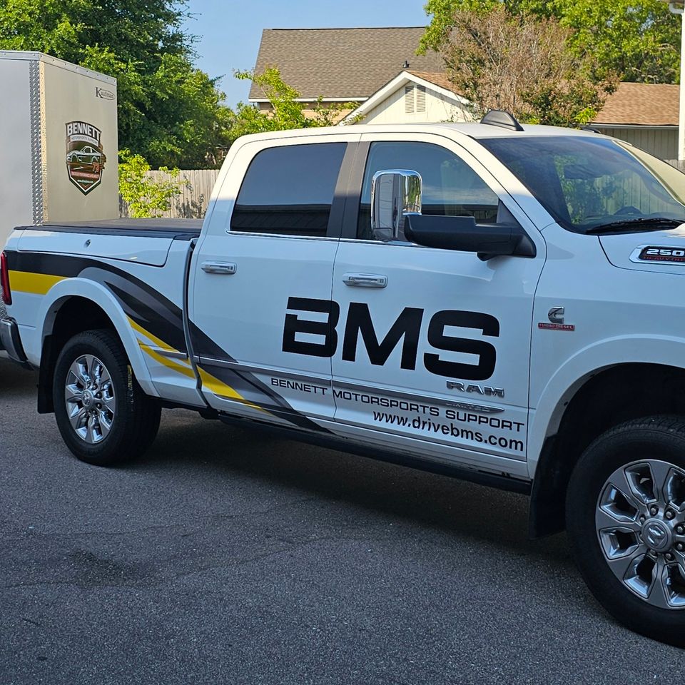 Wide angle view of the Bennett Motorsports Support transport setup showcasing the fully branded BMS trackside logistics trailer