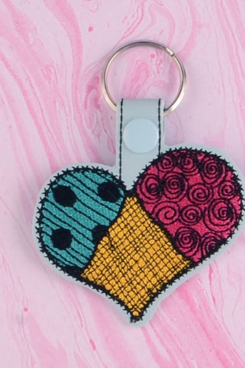 Custom embroidered heart-shaped keychain with patchwork fabric patterns, floral stitching, and vibrant colors.