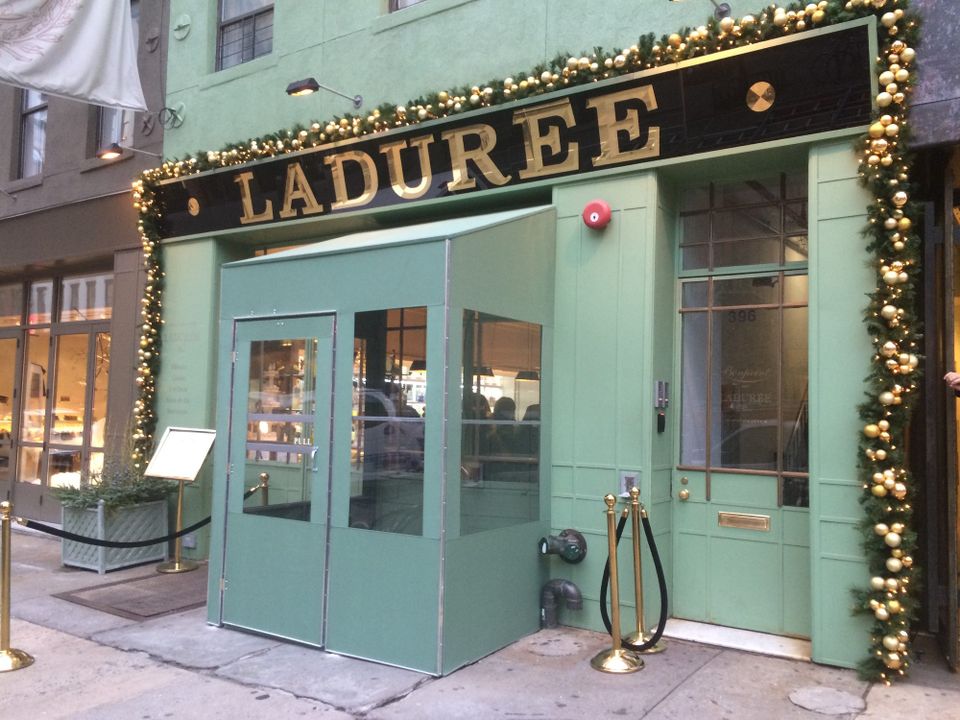 Mint green custom vestibule with glass panels and a double door at the Ladurée storefront, matched to the facade color beneath gold dimensional lettering