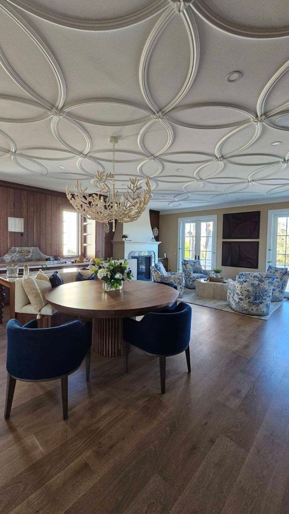 Open living and dining area with detailed ceiling trim and wide plank wood flooring