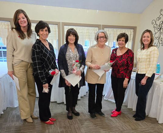 Six women posing together while holding flowers and certificates at a Mahoning Valley Republican Women’s Club event.