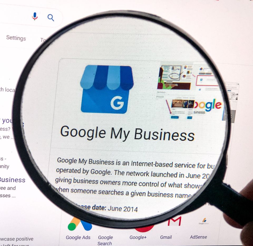 Magnifying glass hovering over a computer screen showing information about Google My Business.