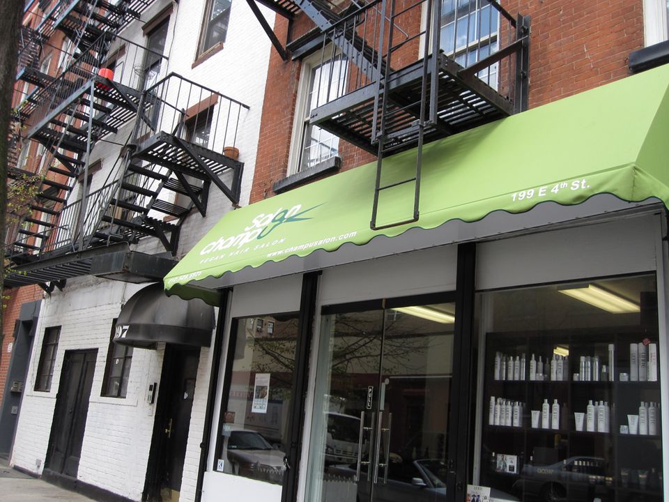 Green storefront awning with printed logo over a salon entrance on East 4th Street in Manhattan