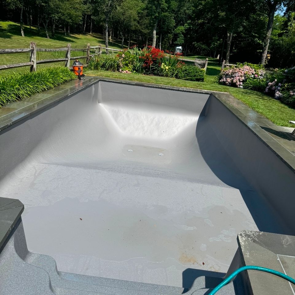 Gray liner installed in a rectangular inground pool with stone coping during a pool renovation