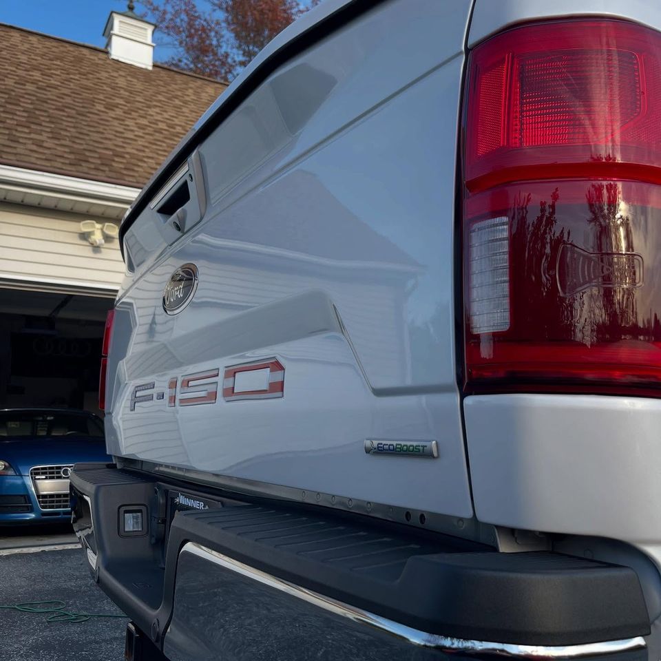 High-gloss Ford F-150 tailgate and taillight reflecting the sky after exterior cleaning