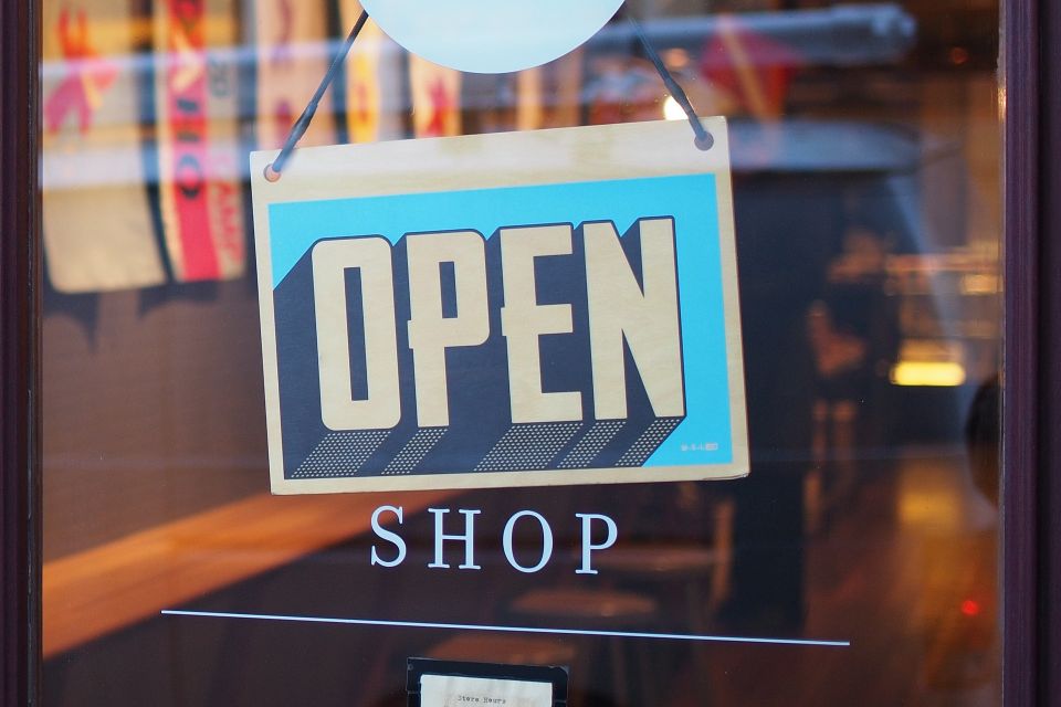 Alltide helps open digital storefront sign in front of small business and sign which reads "Open"