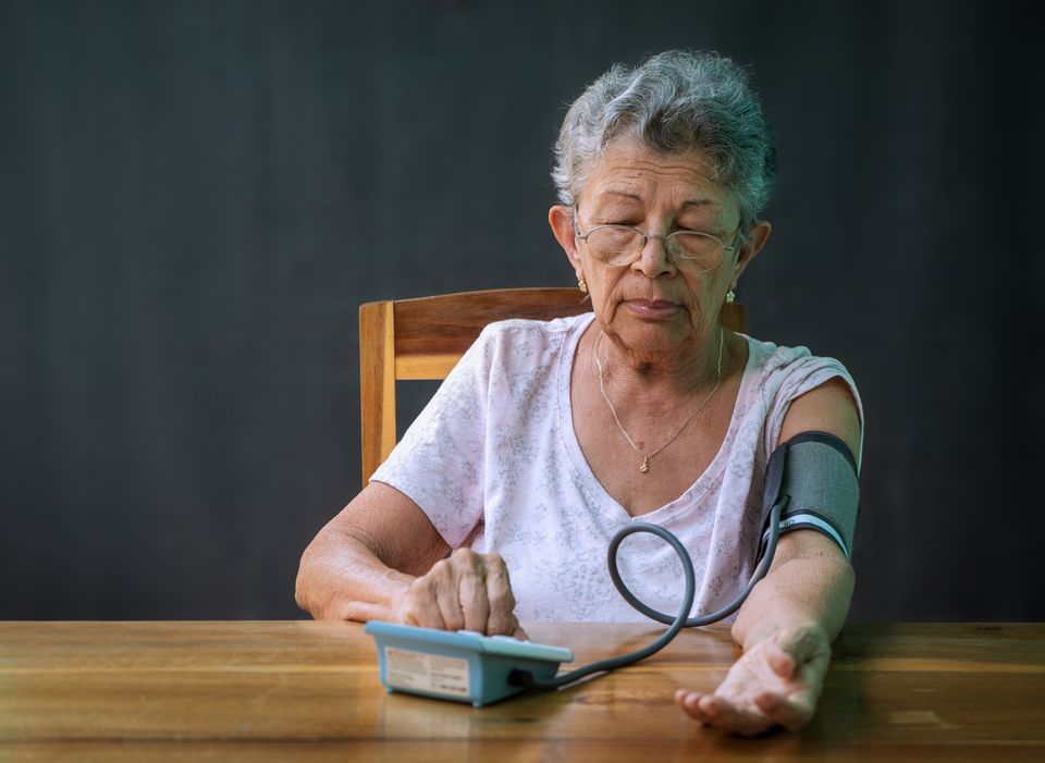 Woman.checking.blood.pressure.at.home.getting.medical.care