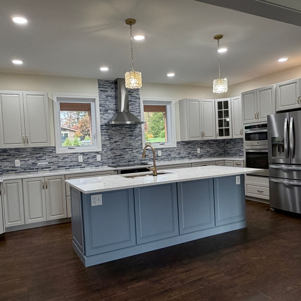 Custom kitchen completed by Manning Construction Co., Inc. featuring custom cabinet, a large center island, quartz countertops, stainless steel appliances, and a tile backsplash.