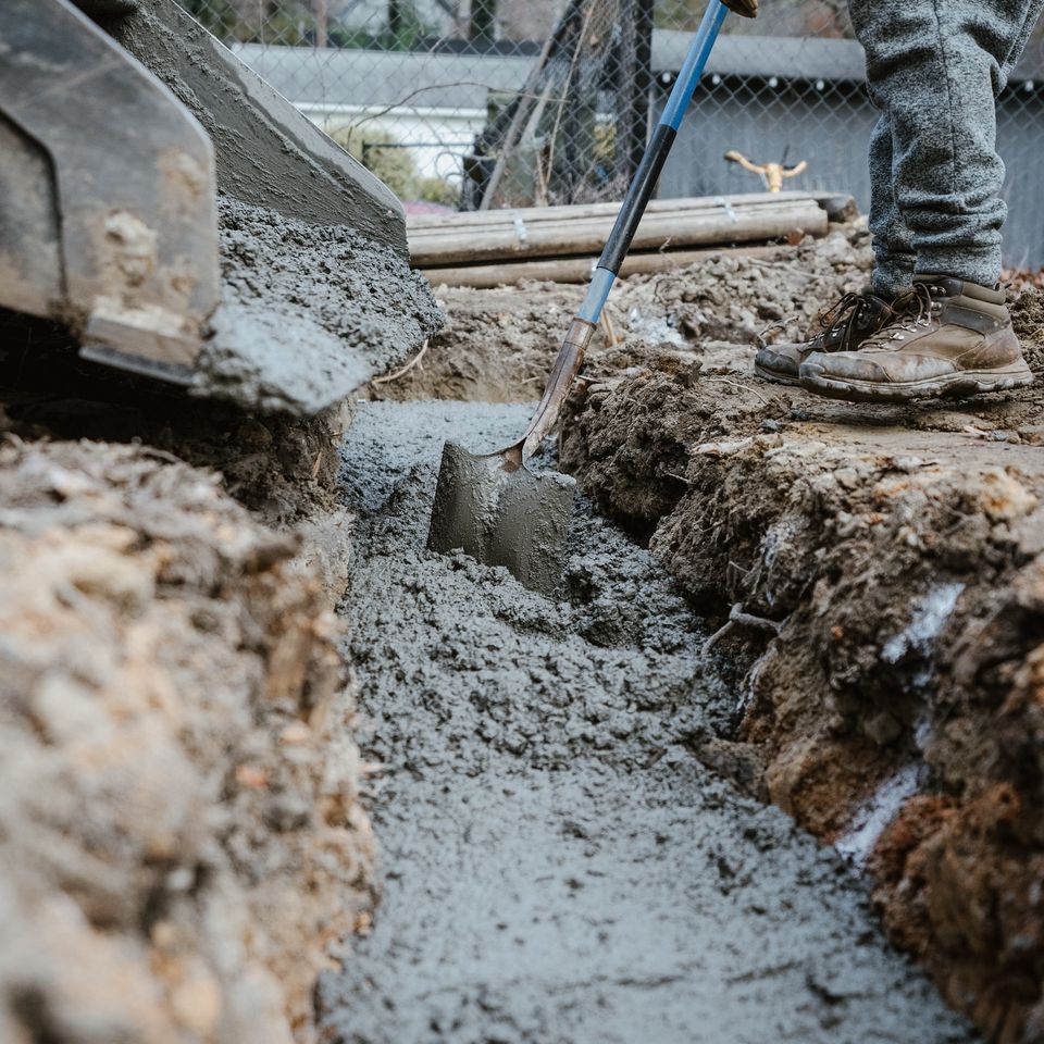 Professional technician pouring fresh cement into a prepared excavation site for a reinforced structural foundation by Roseville Concrete Solutions.