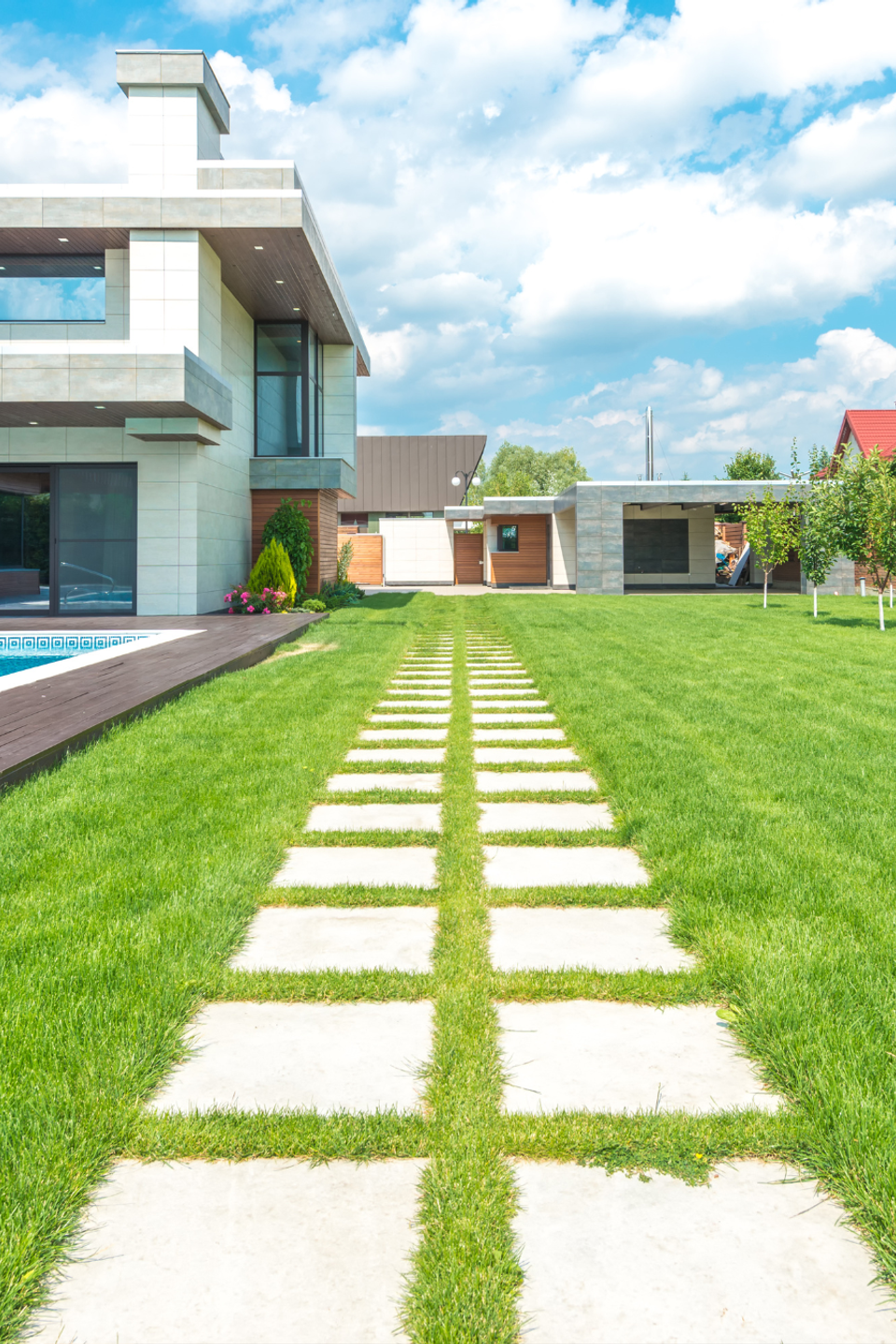 Modern home with a professionally maintained green lawn, stepping stone walkway, and landscaped yard.