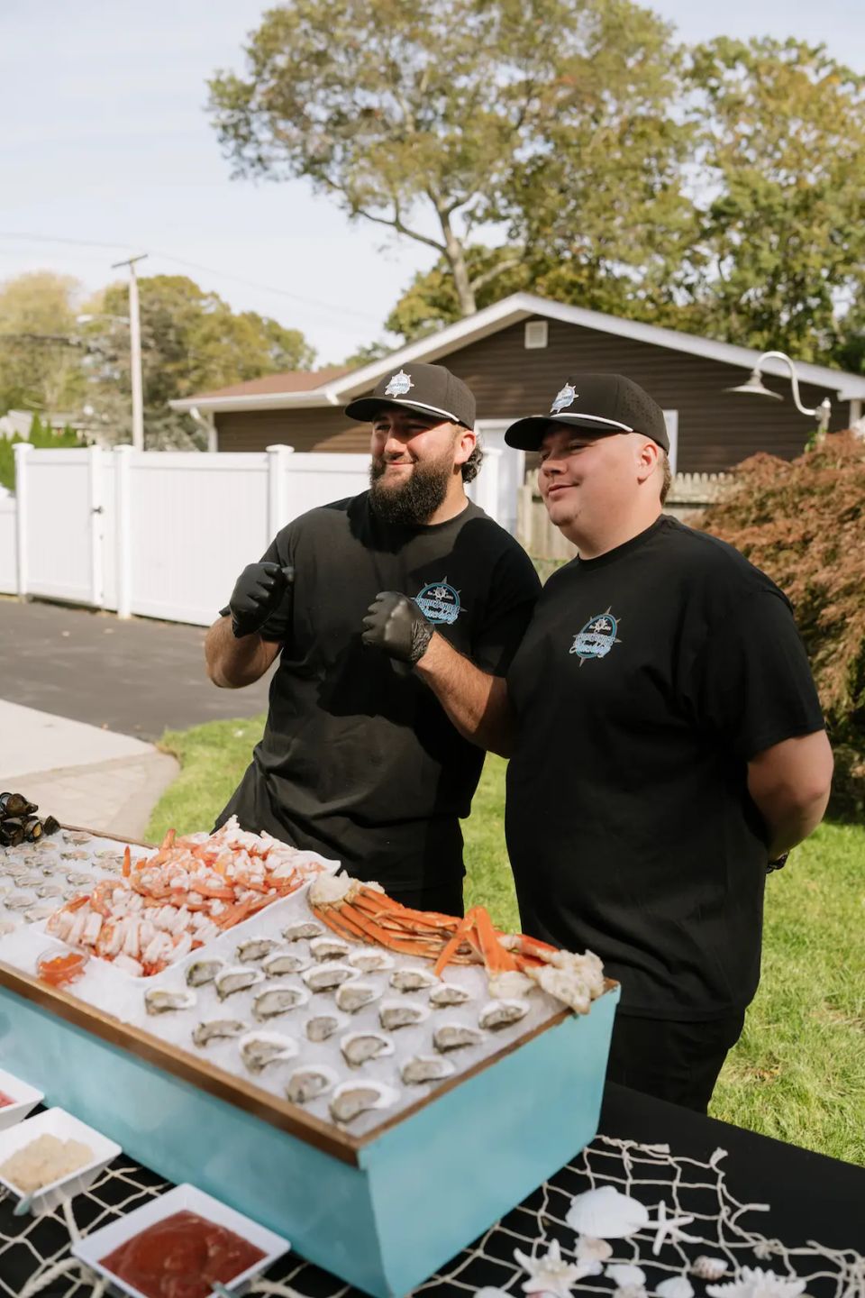 Sean and Mike, the owners of Shore2Shore Shucking, posing for a photo behind their raw bar.