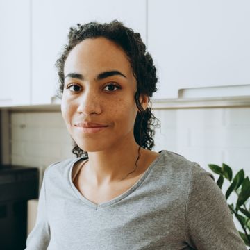 2400 young black woman smiling and looking at camera in kitchen