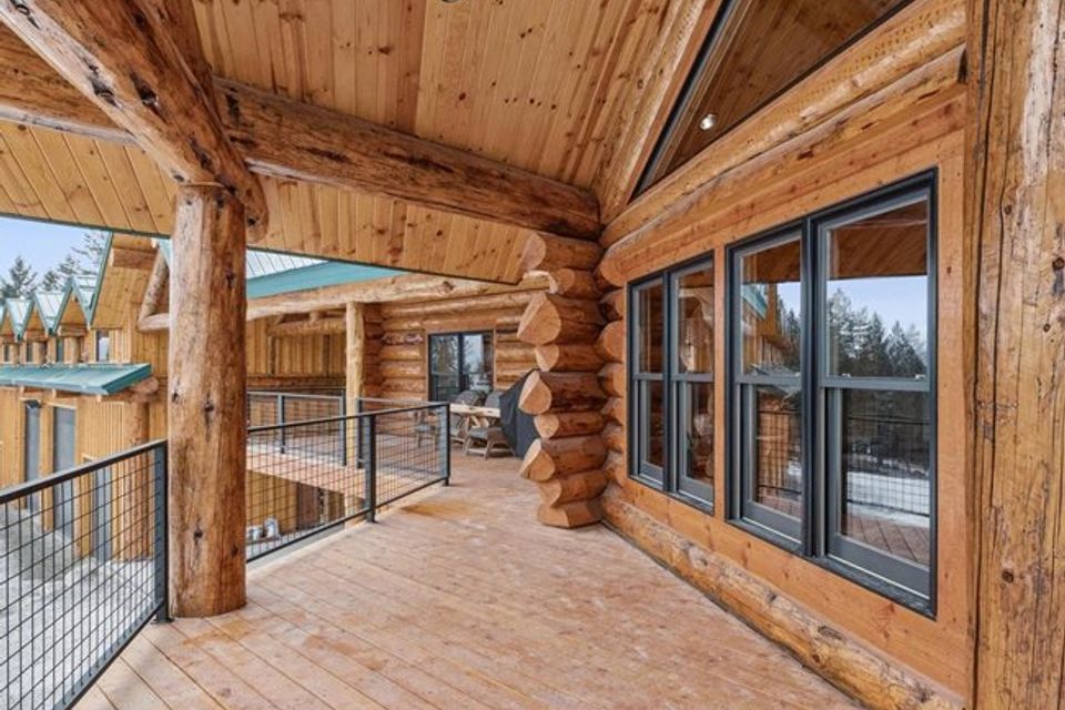 Covered log home deck with round log posts, tongue and groove ceiling, and cable railing