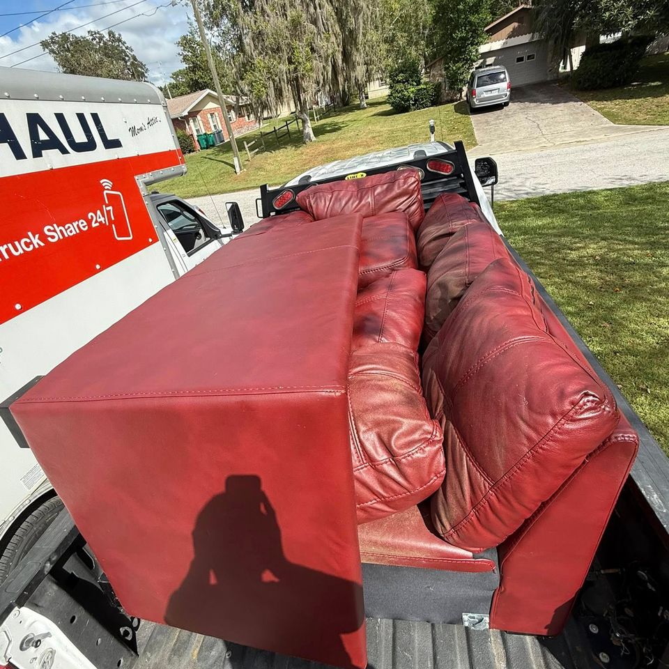 A red couch being transported by JNJ Hauling Solutions of Citrus County
