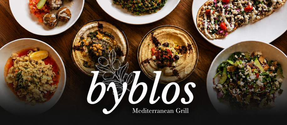 Mediterranean food spread featuring hummus, salads and flatbread from Byblos Mediterranean Grill in Lakeview