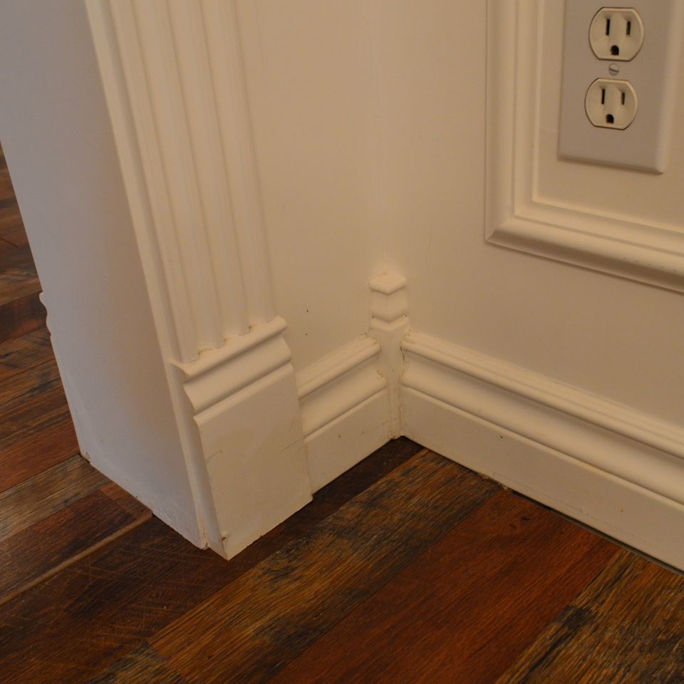 Detail of layered baseboard and plinth block trim meeting hardwood flooring in a custom built home