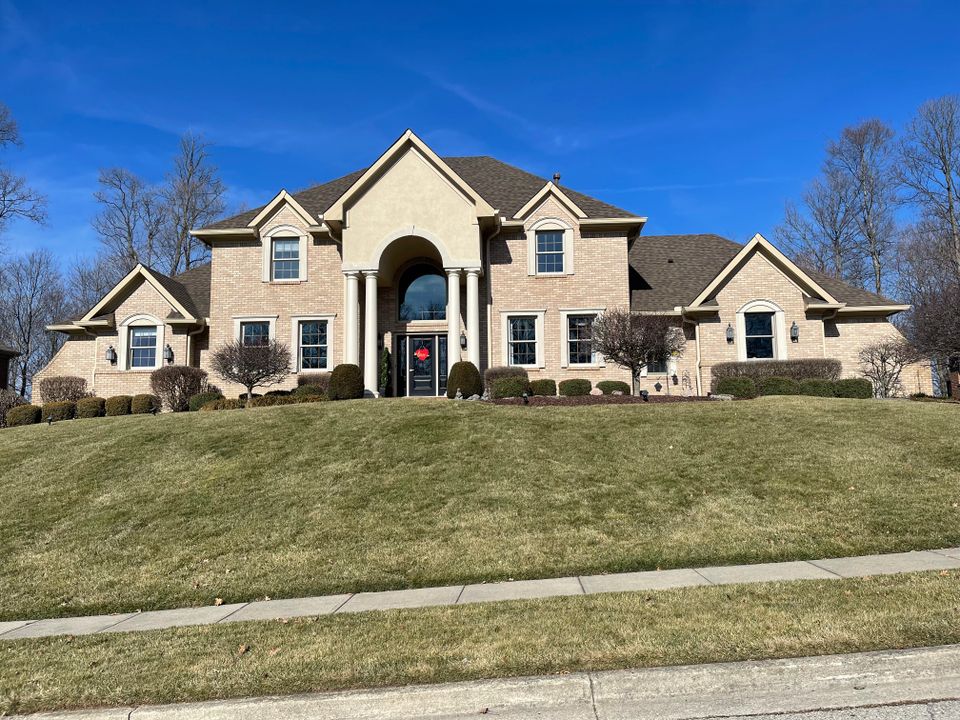 Large two-story brick home featuring a professionally installed by E & D Roofing, Inc.