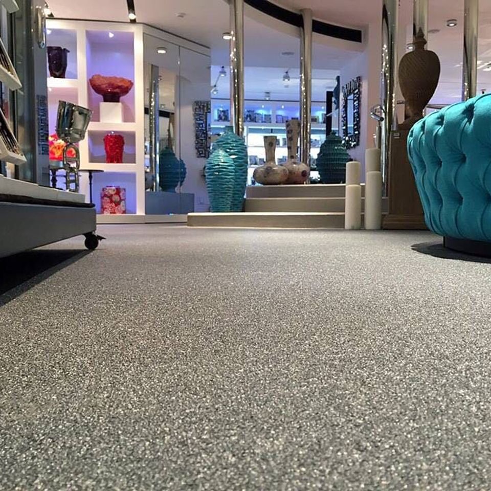 Retail showroom featuring Quartz Carpet flooring with display shelves, decorative furniture, and merchandise.