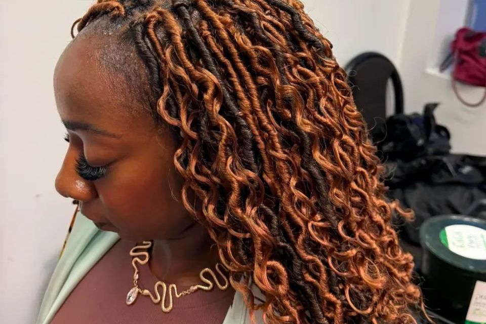 Copper colored distressed locs with curly ends after a braiding service in Los Angeles CA