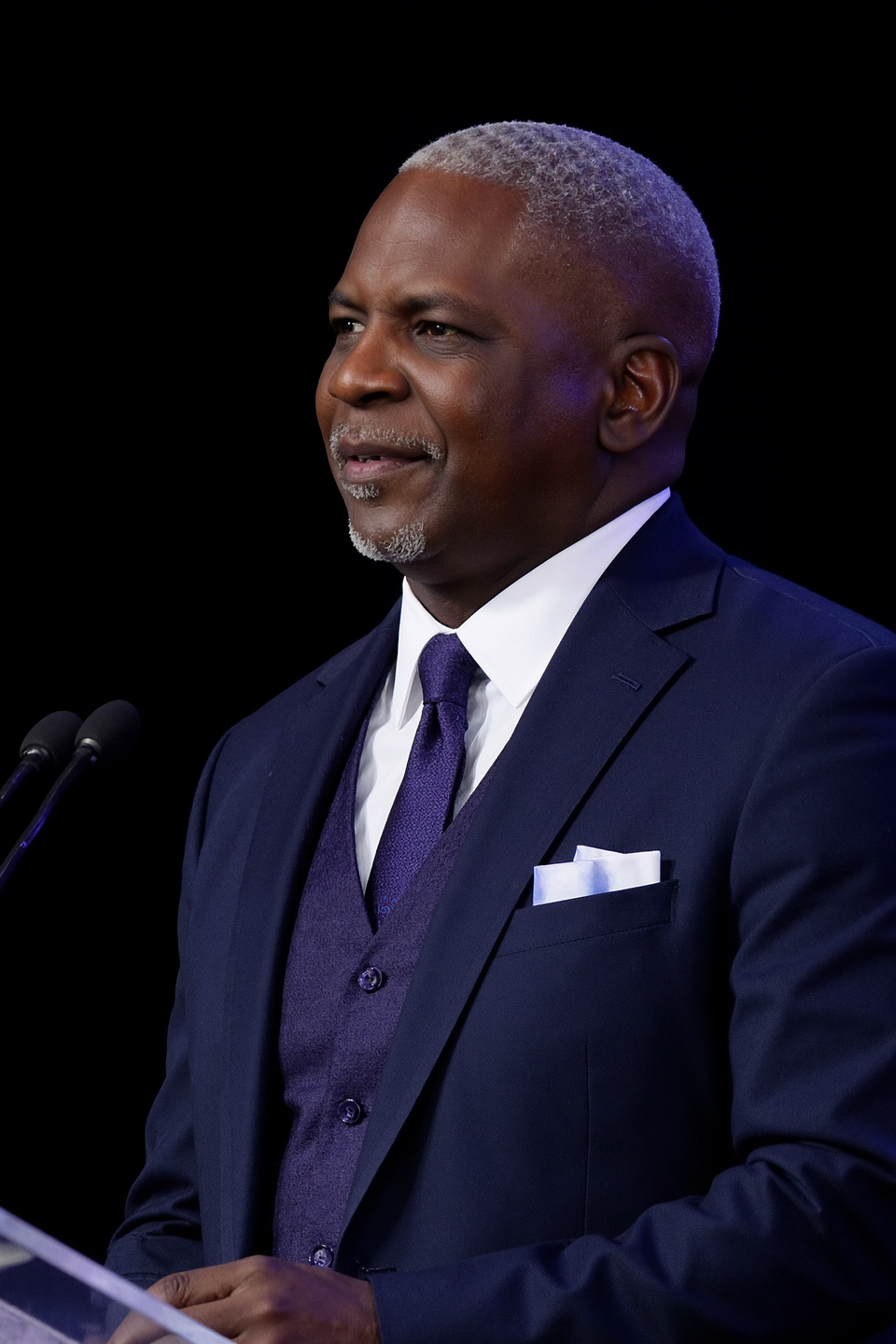 Dr. Curtis Carethers stands at a podium in front of a black background.