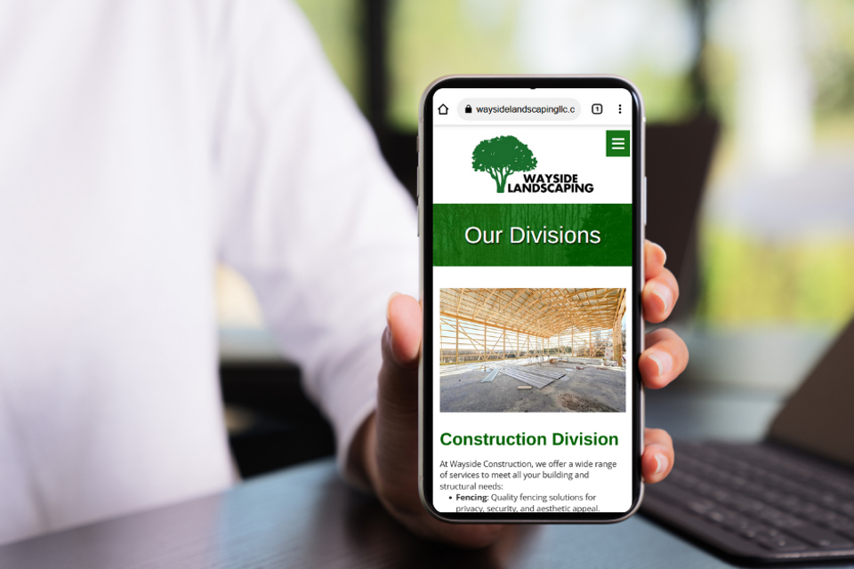 Smartphone displaying Wayside Landscaping and Construction website for Westminster Maryland highlighting construction division services.