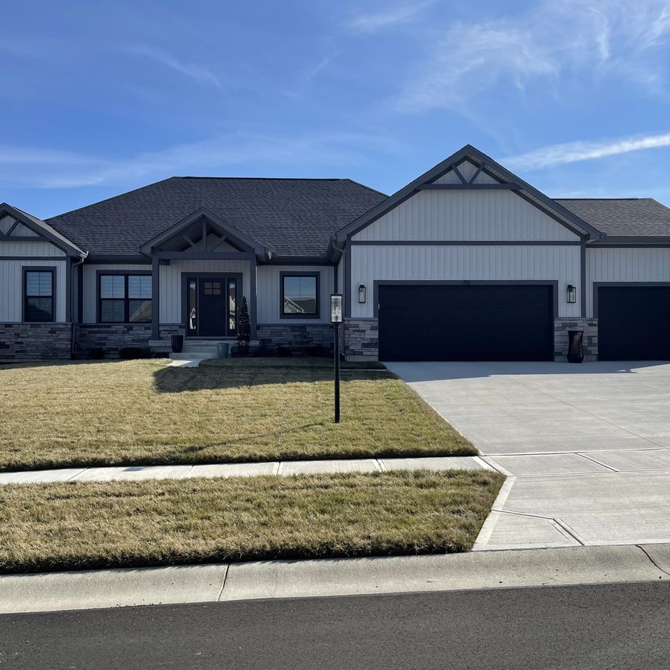 Gray ranch-style home with stone accents and a newly installed dark gray architectural shingle roof by E & D Roofing, Inc.